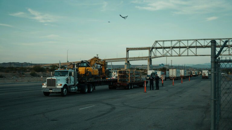 Freight Trucks At A Us-Mexico Border Crossing Near Laredo With A Heavy-Haul Flatbed Carrying Machinery