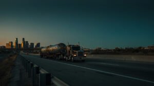 Heavy-haul truck carrying an oversized industrial load on an interstate approaching the Dallas-Fort Worth skyline