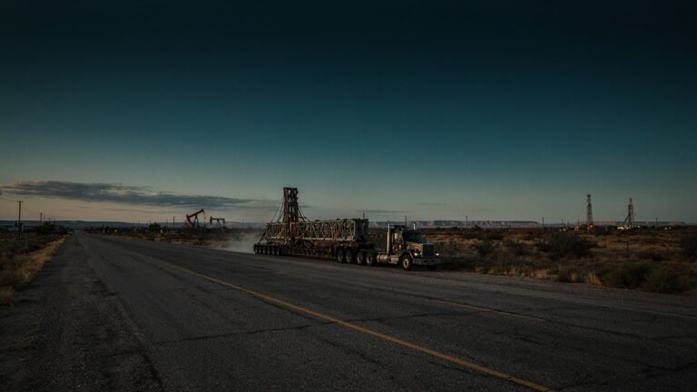 Heavy-Haul Truck Carrying An Oversized Drilling Rig Component On A West Texas Oilfield Highway At Dusk